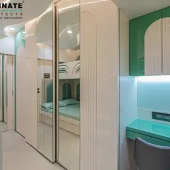 This view highlights the integrated study desk and storage in the kids' room. The mint green desk and cabinets provide a vibrant pop of color against the white, streamlined furniture.