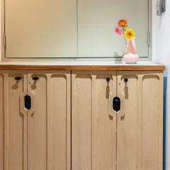 A detail shot of the custom shoe storage cabinet, featuring unique grooved handles that add an organic and modern touch to the entryway.