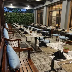 The outdoor seating area for Ebony Restaurant, designed with patterned tile flooring, a living green wall, and comfortable wooden benches to create an inviting al fresco dining experience.