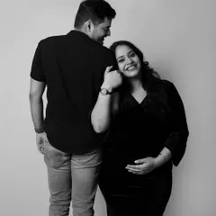 The pure joy of pregnancy shines in this black and white photo. The mother-to-be leans on her partner with a happy smile, a simple and beautiful moment.