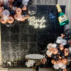 A chic bachelorette party backdrop using a black sequin wall and a white "Bride to be" neon sign for a stylish and modern celebration.
