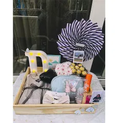 This personalized birthday tray includes a light-up initial 'D', a selection of clothing and accessories, Ferrero Rocher chocolates, and a mini polaroid for that extra personal touch.