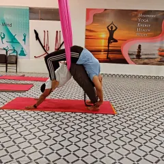 This Acro Yoga pose combines a downward dog from the base with a backbend from the flyer, who is also supported by the aerial silk. It is a great example of how we blend different yoga styles.