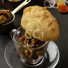 A modern interpretation of a beloved classic, our Chole Bhature. We serve the spiced chickpea curry in a glass cup, topped with a single, perfectly puffed bhatura, transforming a traditional dish into a chic, single-serving experience.