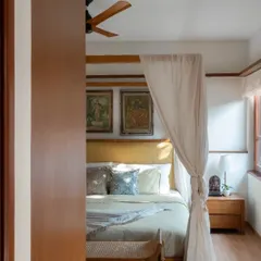 A glimpse into a serene bedroom featuring my Teak Poster Bed. The elegant frame, draped with light fabric, creates a romantic and restful atmosphere, turning the bed into a true retreat.