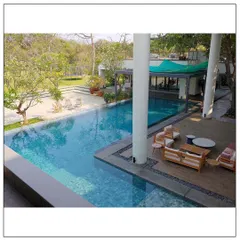 "Home is where the pool is." This Alibaug residence is designed around leisurely outdoor living, with a stunning pool, wooden deck, and seamless connection to the expansive green lawn.