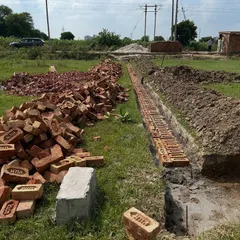 The very beginning of construction: laying the first course of bricks for the foundation trenches. This methodical process ensures the foundation is built on solid ground and to exact specifications.