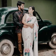 A classic pre-wedding portrait featuring a couple in elegant ethnic wear posing with a vintage car, blending traditional style with a touch of retro charm.