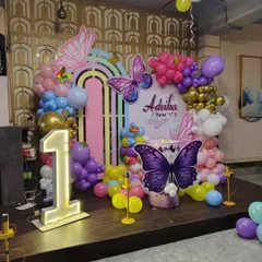 Another angle of the butterfly-themed first birthday party, showing the full arrangement with the cake stand and balloon clusters.