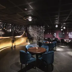 This lounge interior in our 'Moody Blues' project transforms the space into a fluid work of art. The design uses a dark, intimate color palette with plush blue velvet chairs and a dynamically lit, curving bar to evoke a sense of freedom and movement.