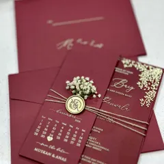 A complete acrylic invitation suite in a deep maroon. This set includes the main acrylic invite, a matching envelope, and a 'save the date' card with a calendar, all tied together with twine and a custom wax seal.