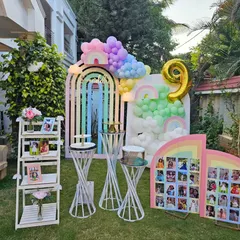 Samriddhi's 9th birthday was a dreamy pastel rainbow party. This outdoor setup includes rainbow-arched backdrops, cloud-like balloon clusters, and a photo milestone board, creating a whimsical and personal celebration.