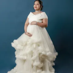 An angelic portrait in a voluminous white ruffled gown against a deep blue studio backdrop, creating a cloud-like effect.