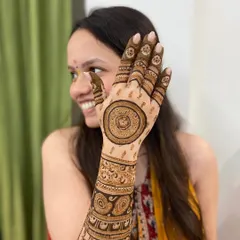 A beautiful, happy bride showing off her intricate mandala and paisley mehendi design.