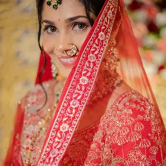 A playful peek from behind the veil. This shot captures the bride's happy smile and the intricate details of her red dupatta and jewelry.