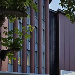 A detailed shot of the facade's vertical elements and fenestration. The rhythmic pattern of the windows and panels creates a dynamic and contemporary look, reflecting the modern workspace design within.