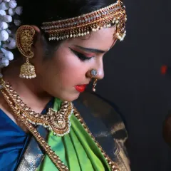 A beautiful candid profile of the dancer during her getting-ready process, highlighting the elaborate jewelry and makeup.