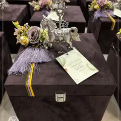 A close-up of a royal-themed baby announcement hamper, presented in a luxurious deep purple velvet chest. The gift is adorned with a silver-plated horse figurine and a custom 'Thank You' tag, making it a grand and memorable keepsake.