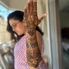 A personalized design with the client's name 'Sangeeta' written beautifully on the arm, along with their initials 'NV'.