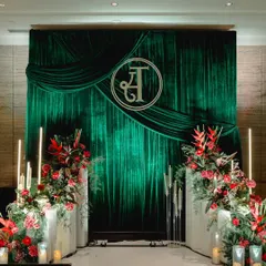 This modern reception backdrop features a rich, emerald green velvet drape, creating a sense of deep luxury. The custom-designed couple's monogram adds a personal and sophisticated touch, making it a unique focal point for the event.