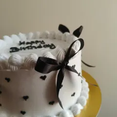 A close-up of the delicate black ribbon bow on this chic vintage cake.