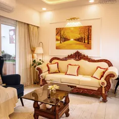 This living room features a classic carved wooden sofa that exudes traditional elegance. The design is balanced with modern touches like soft lighting and contemporary art for a perfect fusion.