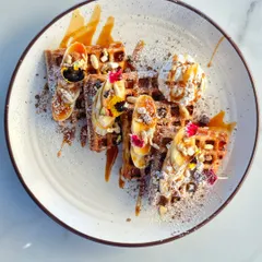 Our signature waffles are a feast for the eyes and the taste buds. Topped with fresh bananas, berries, crunchy nuts, a scoop of vanilla ice cream, and a drizzle of caramel sauce, it's the perfect treat to share or enjoy all to yourself.