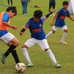 Passion, hustle, and teamwork. A young player skillfully shields the ball from two opponents, showing great strength and ball control.