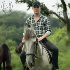 A focused rider on a beautiful grey horse, surrounded by the lush greenery of the Aravallis. This portrait captures the calm and composed atmosphere of our trail rides.