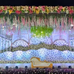 An ethereal reception stage design with waves of white flowers, hanging floral strings, and soft lighting, perfect for a dreamy and elegant evening celebration.
