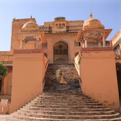 A wide-angle shot of a couple ascending the grand stone staircase of a historic Indian palace. This image captures the scale and majesty of destination pre-wedding locations.