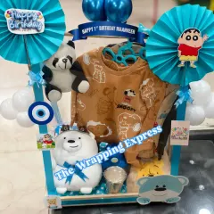A closer look at the Shinchan-themed first birthday hamper, showing the cute character cutouts and a Snoopy sweatshirt.