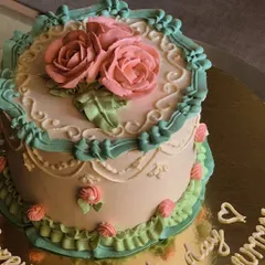I call this vintage design 'Her Highness'. It features intricate piping, delicate ruffles, and soft pastel buttercream roses, perfect for a Mother's Day treat or a classic celebration.