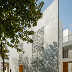 The facade of Vidyashilp Academy features large 'jali'-inspired panels that filter sunlight and maintain constant airflow. This passive design strategy, combined with the preservation of existing trees, creates a climate-responsive and energy-efficient learning environment.