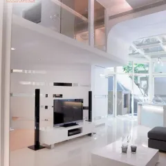 The living area in this modern home features a sleek TV unit and a double-height ceiling with glass, which floods the space with natural light.