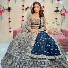 The bride is seated, showcasing her magnificent navy and silver lehenga for her sangeet ceremony.