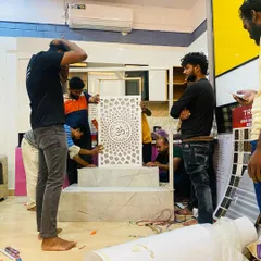Our team carefully assembles a custom pooja mandir at our office. This image captures the moment we install the beautiful 'Om' panel, a centerpiece of the design.