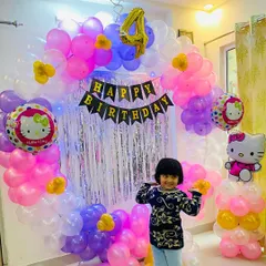 A happy moment from a 4th birthday party we photographed. This image shows the birthday girl posing in front of a custom Hello Kitty themed balloon arch and shimmer backdrop we designed for her special day at home.