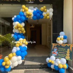The entrance to a naming ceremony featuring a Krishna theme. A large balloon arch in blue, white, and gold welcomes guests, complemented by a themed welcome sign.