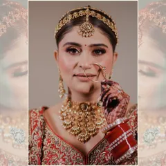 A classic bridal portrait. The bride, adorned in gold jewelry, gently holds her nath (nose ring), drawing attention to the traditional details of her wedding look.