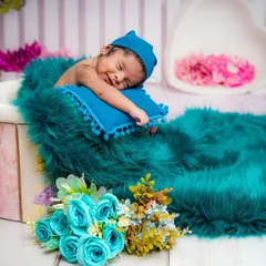 Capturing the sweetest dreams. This newborn is smiling peacefully, nestled in a cozy teal blanket. I use soft lighting and comfortable props to ensure your baby is safe and content throughout the session.