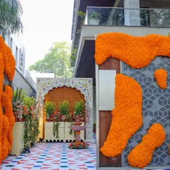 The entrance to the brunch, featuring walls covered in organic-style marigold arrangements and a beautifully crafted niche with a floral backdrop. The custom floor print adds to the immersive experience.