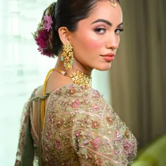 The delicate embroidery of the lehenga is mirrored in the soft, detailed makeup. This look from the back shows how the floral hairstyle and glowing skin come together for a cohesive, beautiful bridal style.