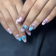 Get into a summer mood with these beach-themed nails. The design features a pink and blue base with hand-painted black palm tree silhouettes.