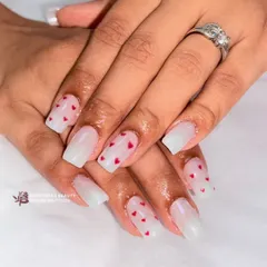 Sweet and simple. This design features a sheer, milky white base on square nails, adorned with tiny, hand-painted red hearts for a touch of romance.