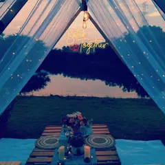 The view from inside the intimate tent setup at dusk. The combination of fairy lights, candles, and the neon sign creates a magical ambiance for a romantic dinner celebration.