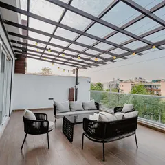 A stylish balcony retreat with a pergola. The comfortable outdoor furniture is perfect for relaxing, and the string lights add a warm and festive glow in the evenings.
