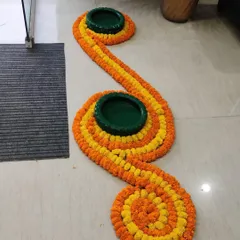 A simple yet elegant floor decoration for an entryway. I used yellow and orange marigold strings to create a winding pattern, with green matkas (earthen pots) placed as decorative accents.