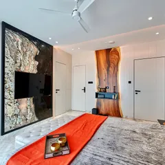 We love using natural materials in unexpected ways. This bedroom features a TV panel made from a unique stone slab and a desk area highlighted by a live-edge wood piece, creating a design that is both rustic and modern.