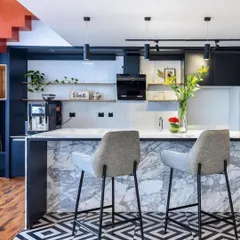 A stylish pantry and bar area within the coworking space, featuring a marble-clad island and bold geometric floor tiles. It's designed to be a social spot for coffee, lunch, or casual networking.